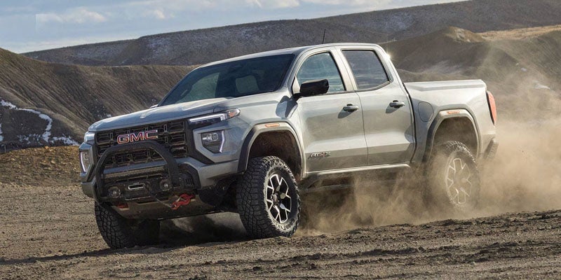 Silver 2026 GMC Canyon AT4X driving through dirt terrain off-road
